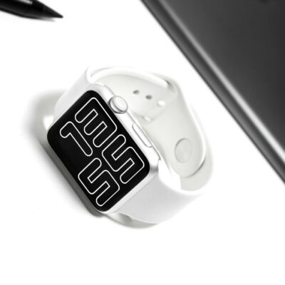 A sleek white smartwatch with a digital display on a minimalist desk setup.