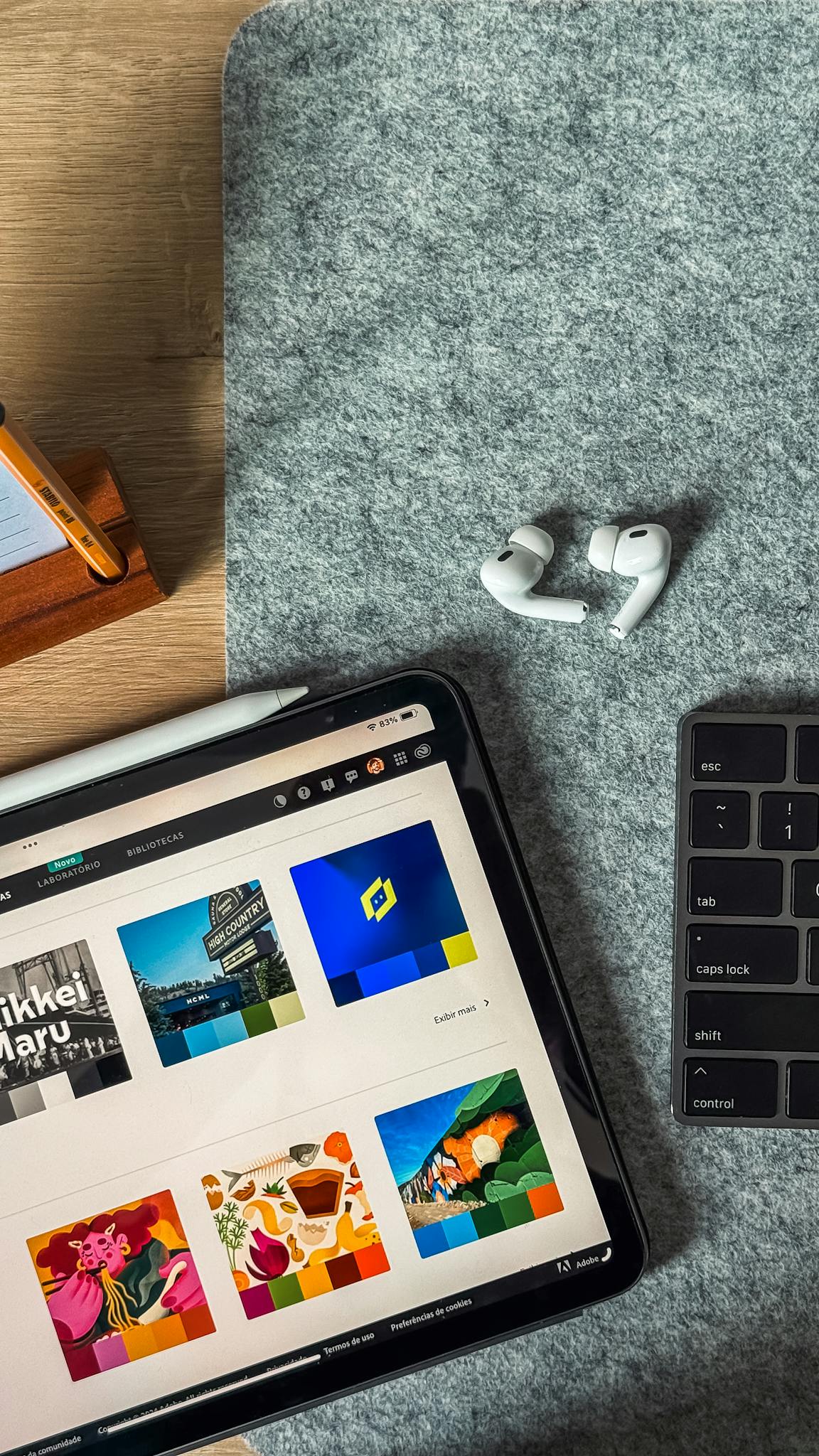 A top view of a sleek workspace featuring an iPad, AirPods, and keyboard on a felt surface.