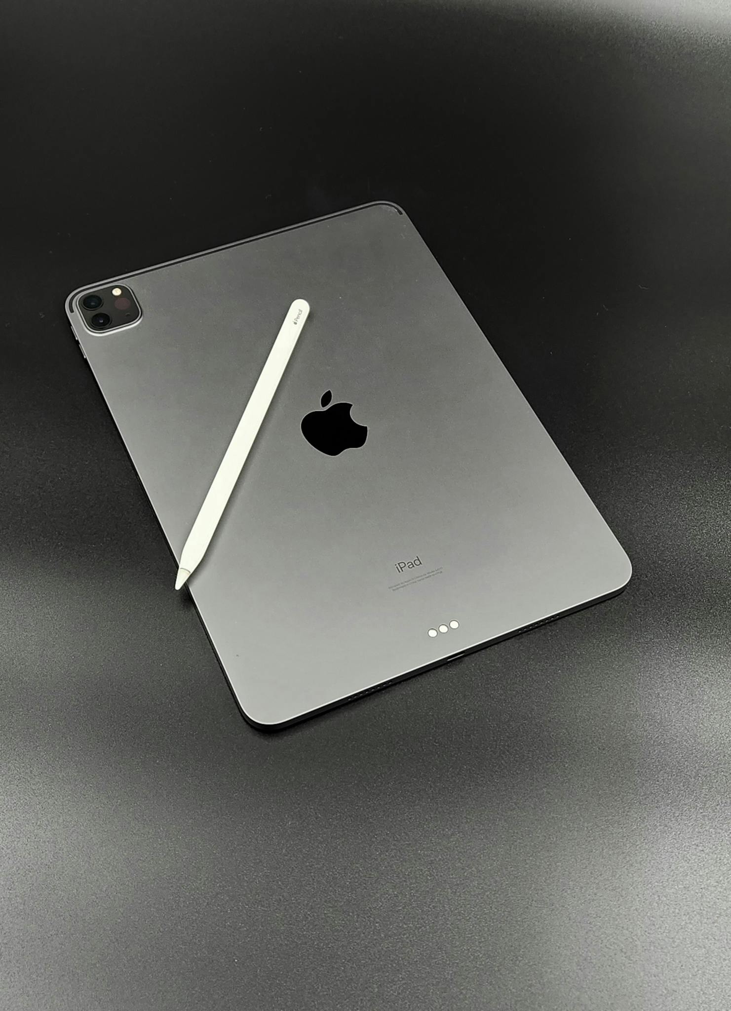 Apple iPad with Apple Pencil on a sleek black surface, showcasing minimalist design.