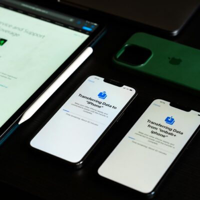 High-angle view of digital devices including iPhones and an iPad on a desk, showcasing data transfer.