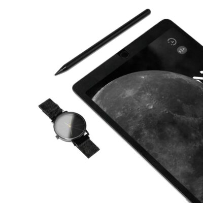 Stylish flat lay of a tech-focused desk with a tablet, stylus, and watch, emphasizing minimalistic elegance.