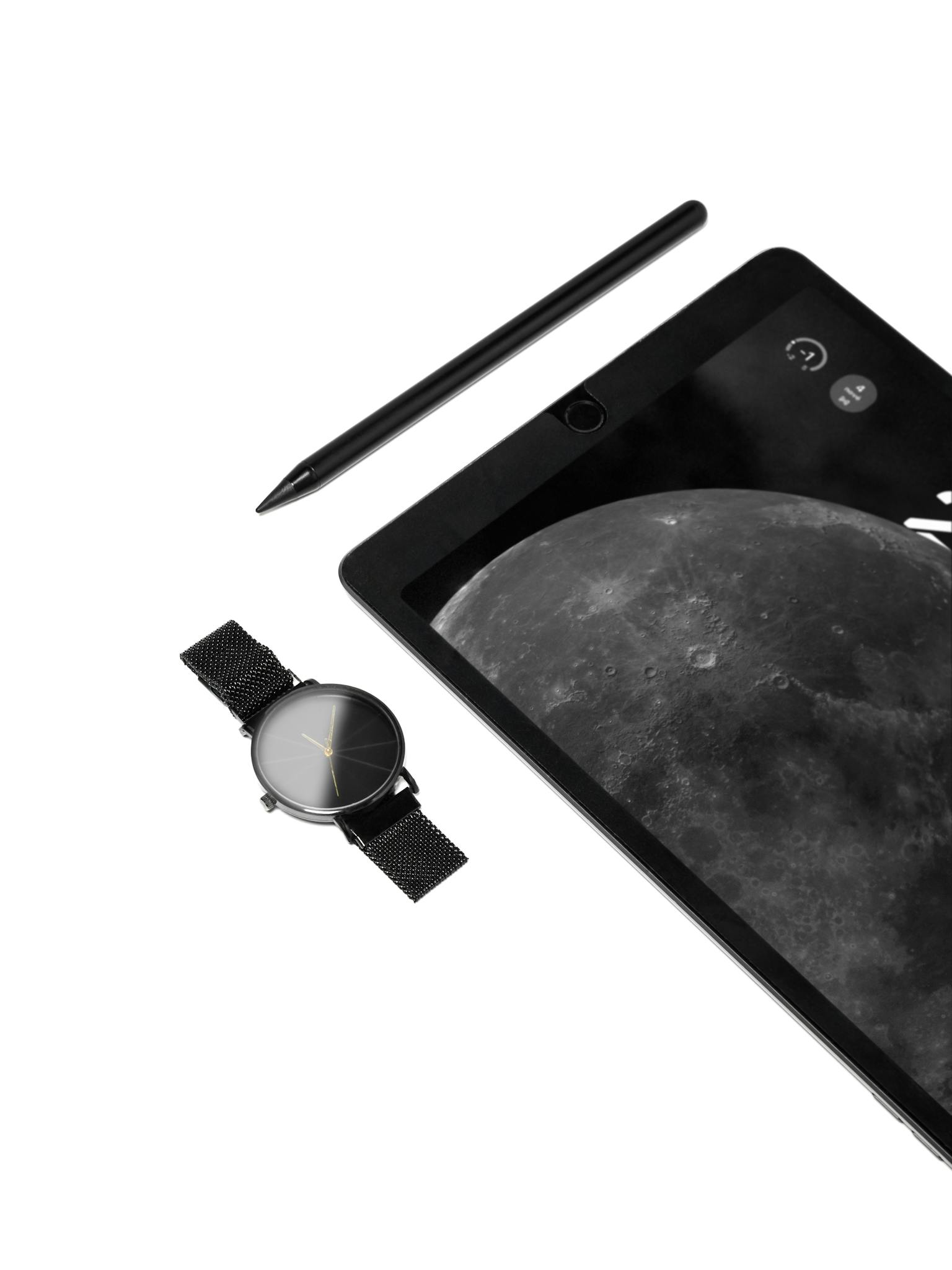 Stylish flat lay of a tech-focused desk with a tablet, stylus, and watch, emphasizing minimalistic elegance.